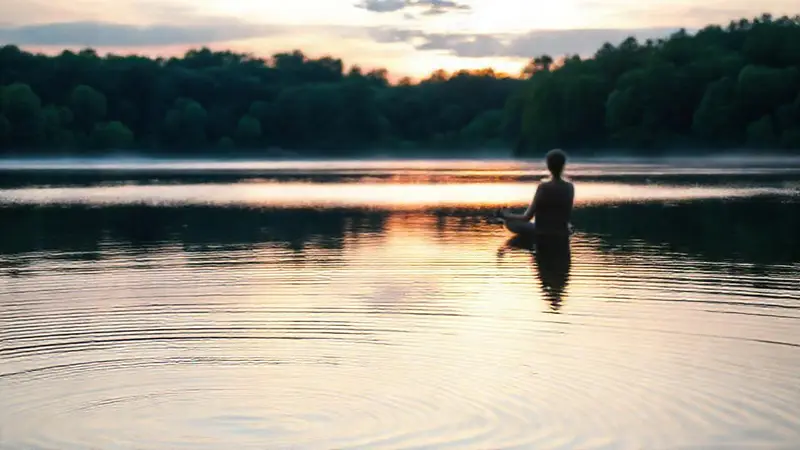 Persona meditando en un lago sereno