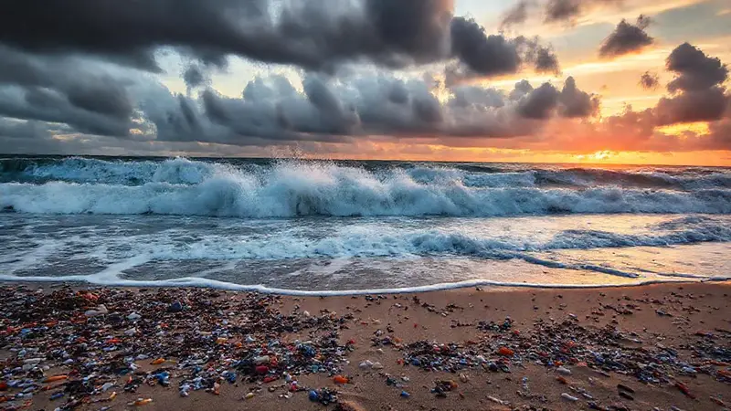 Olas golpean una playa contaminada y sombría