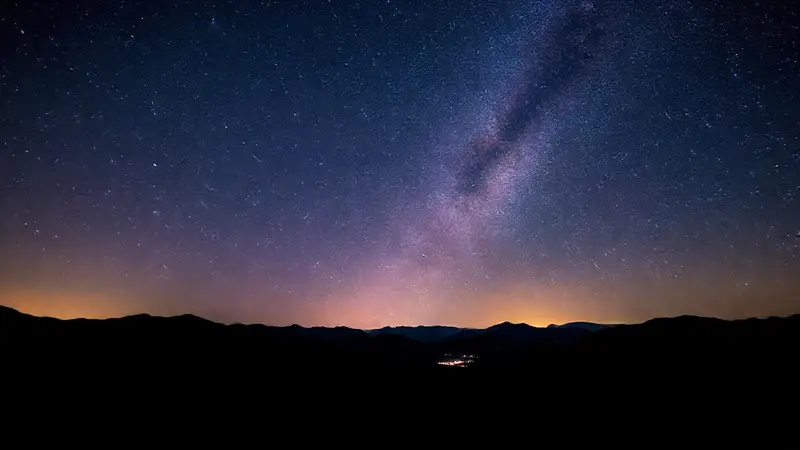Noche estrellada con meteoros y montañas