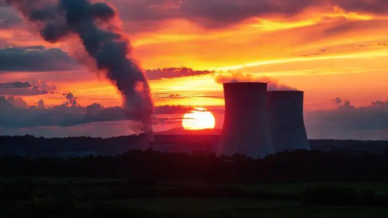 Planta nuclear al atardecer, tensión energía-naturaleza
