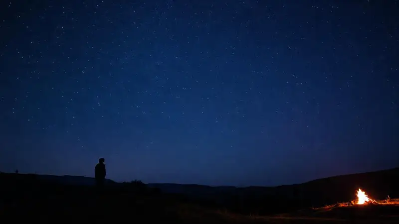 Cielo estrellado con figura solitaria y fogata